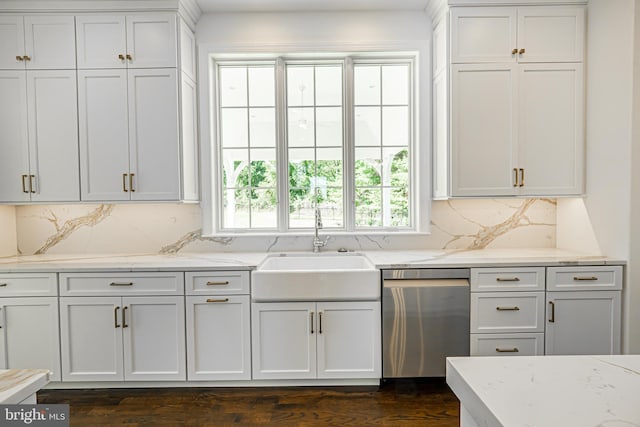 kitchen with tasteful backsplash, stainless steel dishwasher, light stone countertops, a sink, and white cabinets