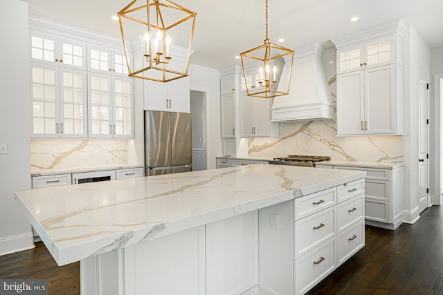 kitchen featuring freestanding refrigerator, premium range hood, stove, and a chandelier