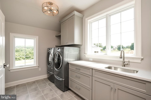 laundry area featuring baseboards, washer and clothes dryer, a sink, cabinet space, and light tile patterned floors