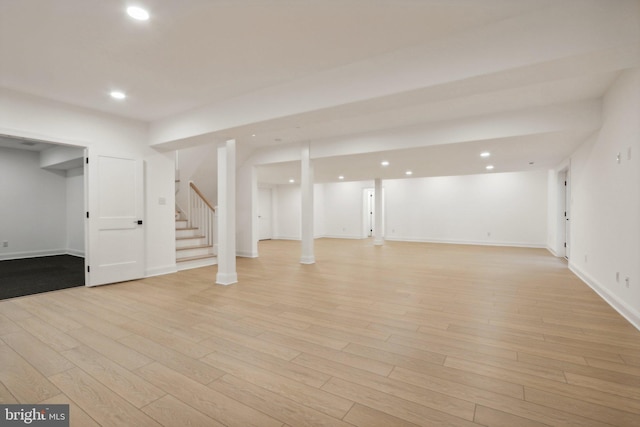 finished below grade area featuring light wood-style floors, recessed lighting, and stairs