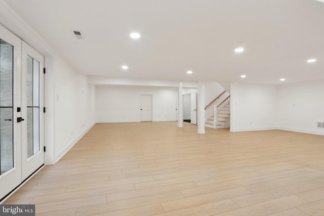 finished below grade area with visible vents, stairway, recessed lighting, french doors, and light wood-style flooring