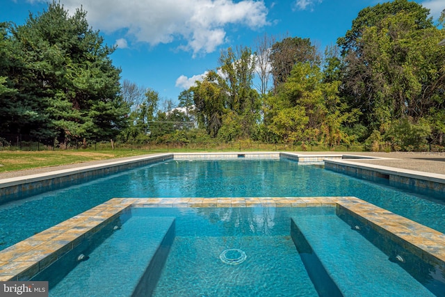 view of swimming pool with a pool with connected hot tub and fence
