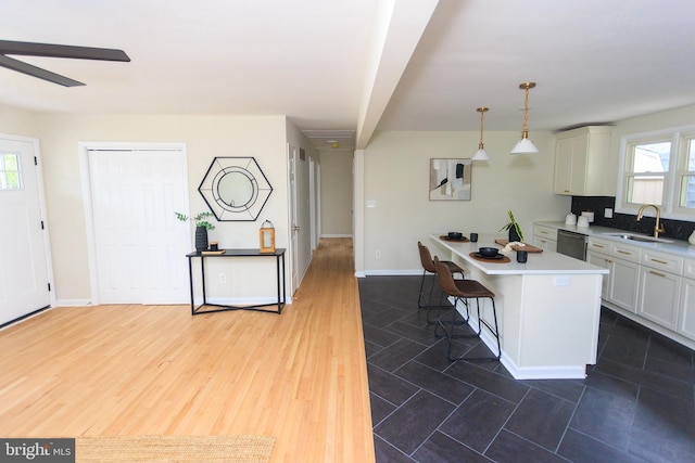 kitchen featuring a sink, dishwasher, light countertops, and white cabinetry