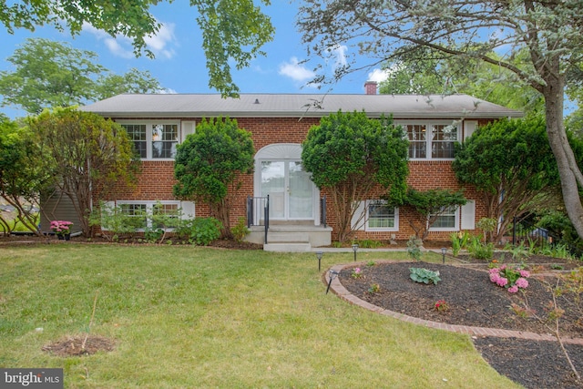 raised ranch with brick siding, a chimney, and a front yard
