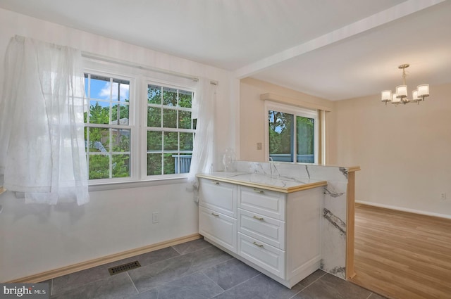 kitchen featuring white cabinets, a notable chandelier, visible vents, and a wealth of natural light