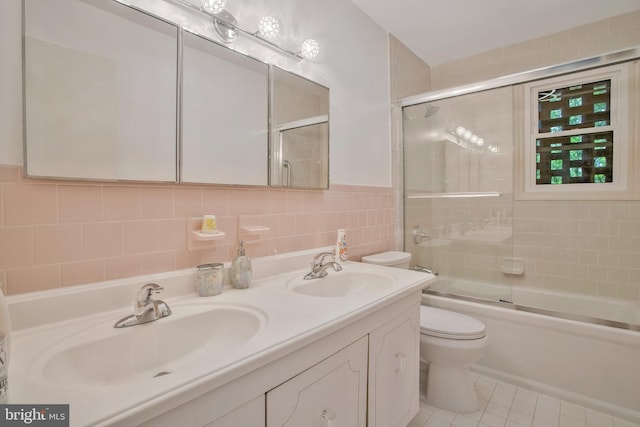 bathroom with a sink, tile patterned floors, toilet, and tile walls