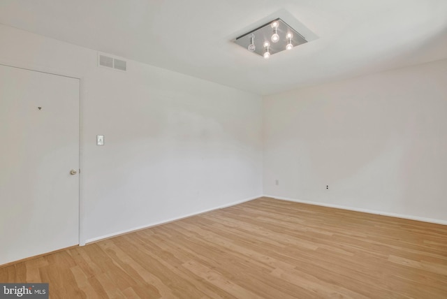 empty room with visible vents, baseboards, and wood finished floors
