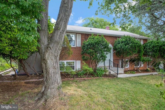 bi-level home featuring a chimney, a front lawn, and brick siding
