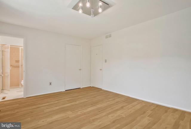 spare room featuring baseboards, visible vents, and light wood finished floors