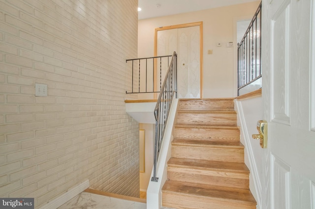 stairway featuring brick wall