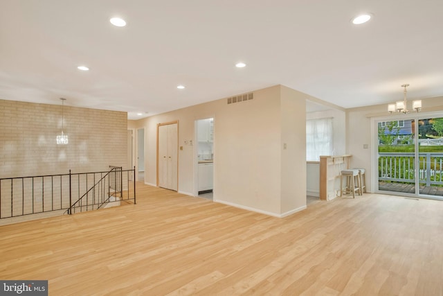 spare room with an inviting chandelier, baseboards, wood finished floors, and visible vents