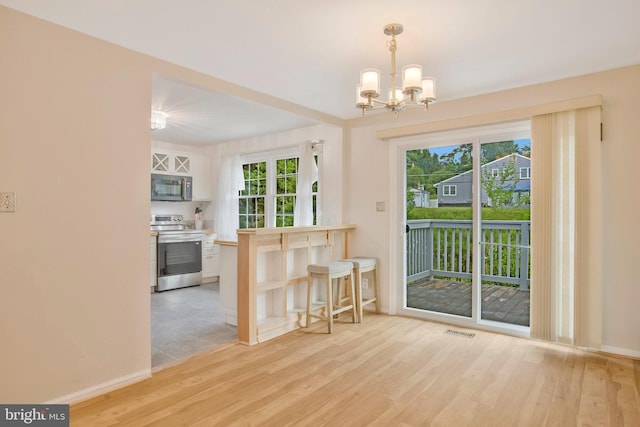 dining space with baseboards, light wood finished floors, a chandelier, and visible vents