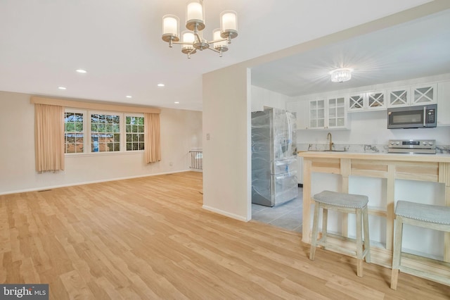 kitchen featuring glass insert cabinets, light wood-style floors, light countertops, white cabinetry, and stainless steel appliances