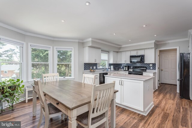 kitchen featuring a kitchen island, backsplash, light countertops, black appliances, and white cabinetry