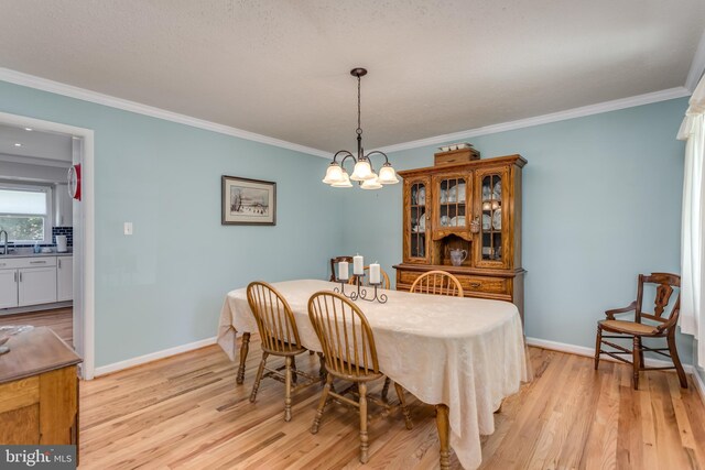 dining room with ornamental molding, light wood finished floors, and a chandelier