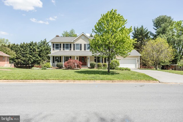 colonial inspired home featuring an attached garage, a porch, a front yard, a chimney, and concrete driveway