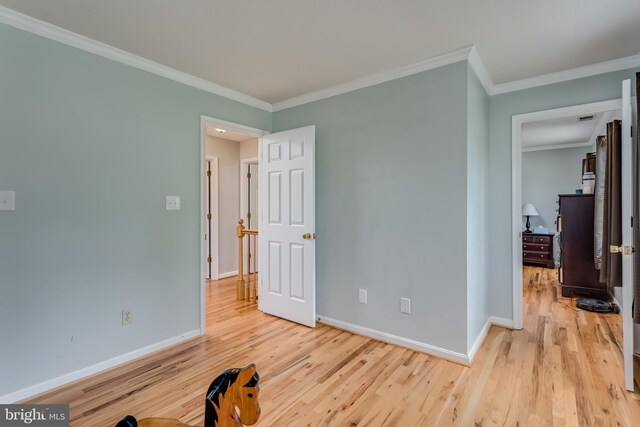 unfurnished bedroom with crown molding, baseboards, and light wood-style flooring