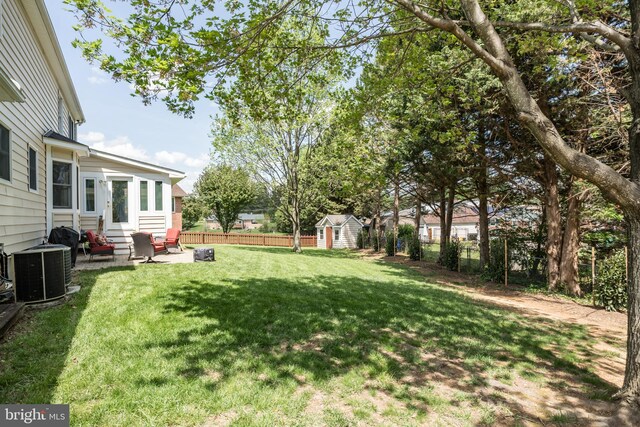 view of yard with an outdoor structure, cooling unit, a fenced backyard, a storage unit, and entry steps