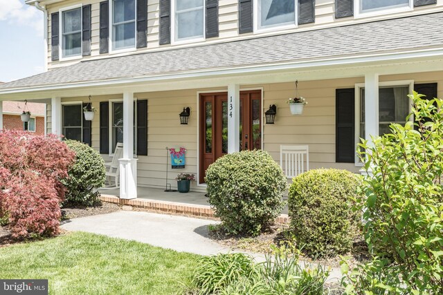 property entrance with a porch and roof with shingles