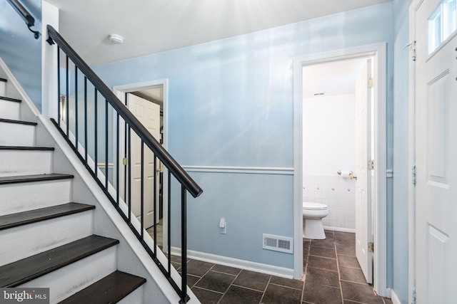 stairs featuring tile walls, baseboards, and visible vents