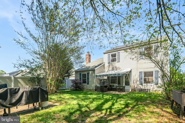 back of property with a patio, a fenced backyard, a yard, and a chimney