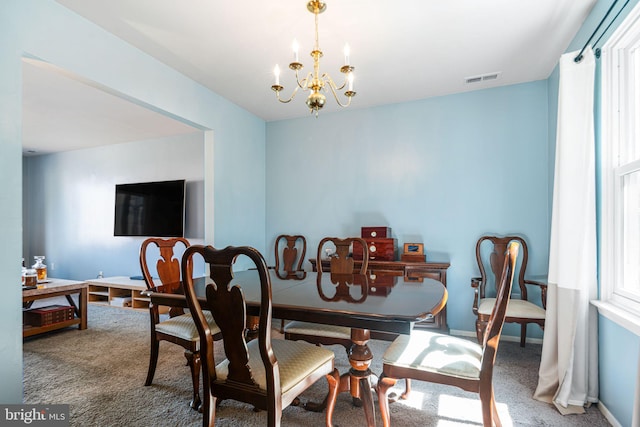 carpeted dining room featuring a chandelier and visible vents
