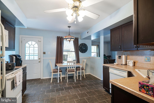 kitchen featuring light countertops, dark brown cabinetry, a healthy amount of sunlight, and white appliances