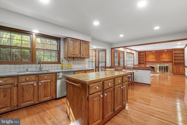 kitchen with decorative backsplash, butcher block counters, light wood-style floors, a sink, and dishwasher