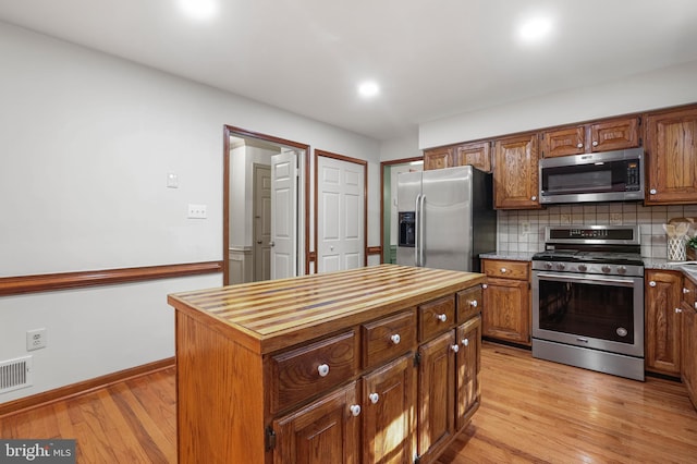 kitchen featuring appliances with stainless steel finishes, wood counters, light wood-style flooring, baseboards, and decorative backsplash