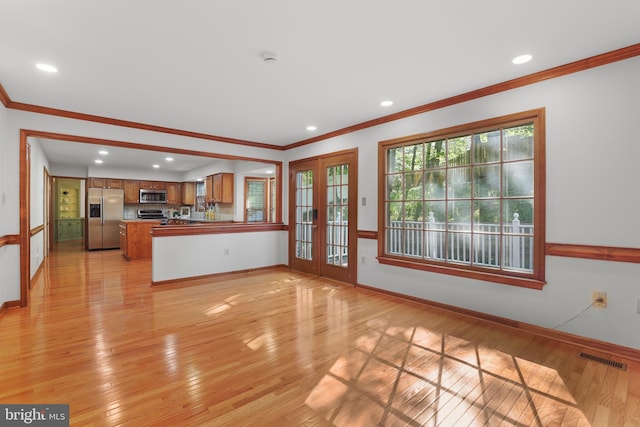 unfurnished living room with baseboards, ornamental molding, french doors, and light wood-type flooring