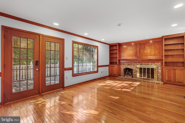 unfurnished living room featuring a brick fireplace, light wood-style flooring, recessed lighting, baseboards, and ornamental molding