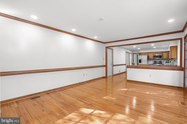 unfurnished living room featuring baseboards, visible vents, ornamental molding, and light wood-style flooring