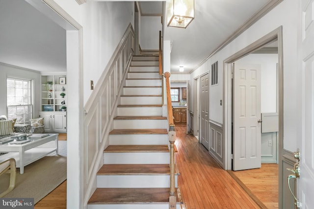 stairs with ornamental molding, hardwood / wood-style floors, and visible vents