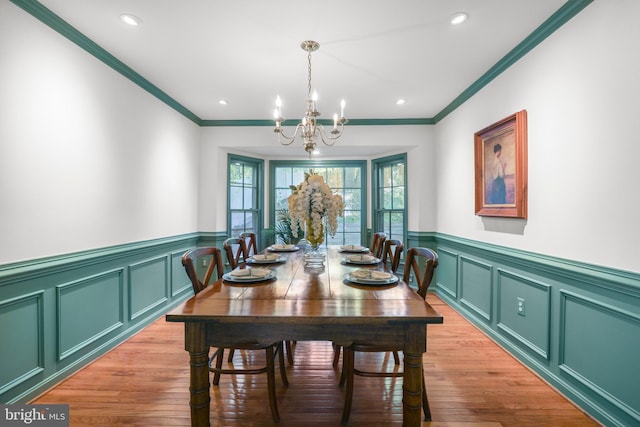 dining space with a decorative wall, a notable chandelier, ornamental molding, and a wainscoted wall