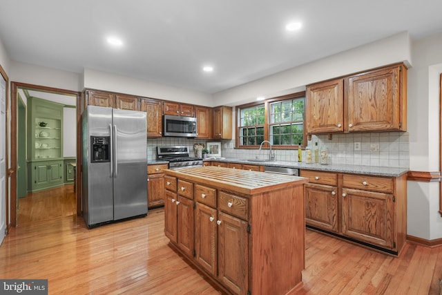kitchen featuring light wood-style floors, brown cabinetry, a kitchen island, and stainless steel appliances