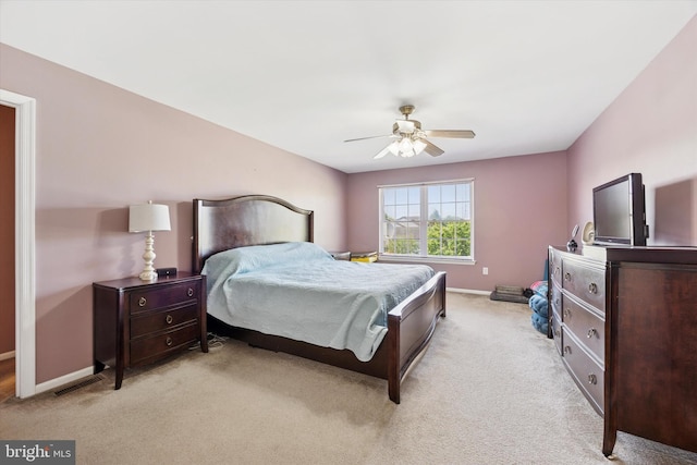bedroom featuring baseboards, ceiling fan, visible vents, and light carpet