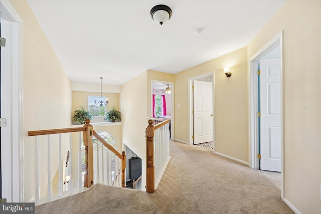 corridor featuring baseboards, carpet flooring, and an upstairs landing