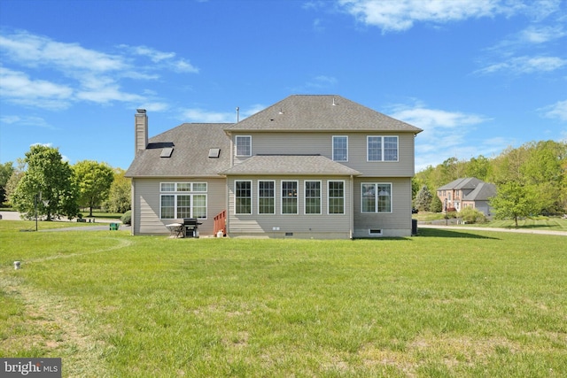 rear view of house featuring a yard, a chimney, and a shingled roof