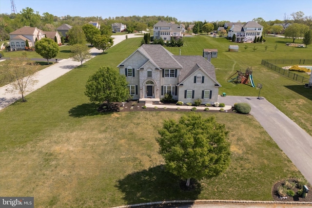 view of front of home featuring a playground, fence, a residential view, and a front yard