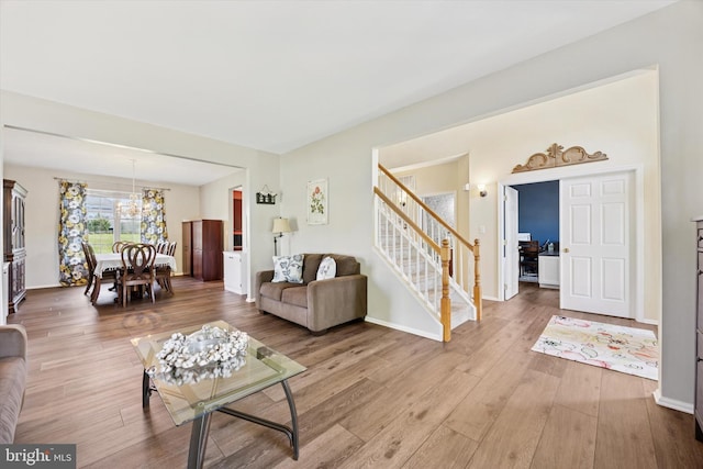 living area with baseboards, a chandelier, wood finished floors, and stairway