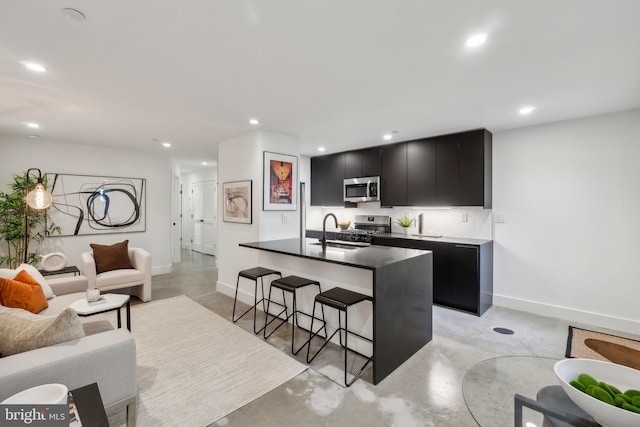 kitchen featuring finished concrete flooring, dark cabinetry, and stainless steel appliances