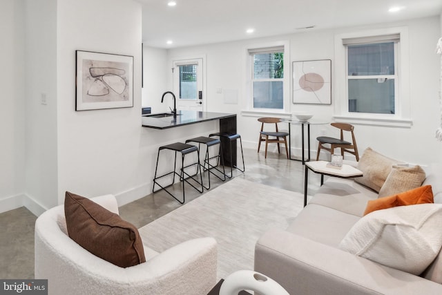 living room with recessed lighting, baseboards, and concrete floors