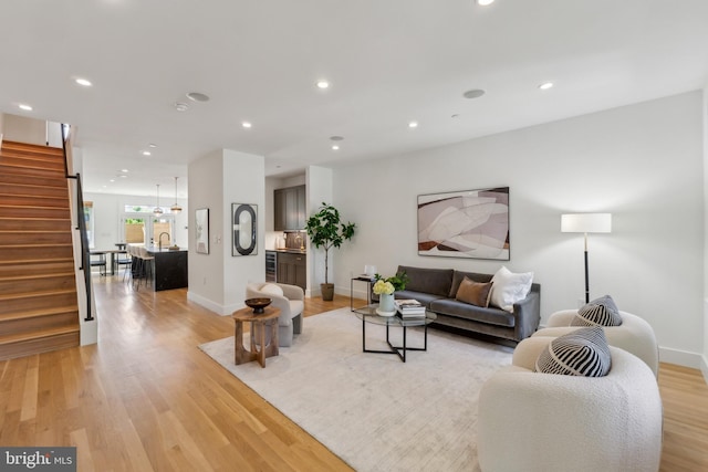 living area featuring light wood-style floors, recessed lighting, baseboards, and stairway