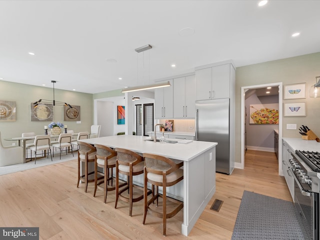kitchen with a sink, a breakfast bar area, recessed lighting, premium appliances, and visible vents