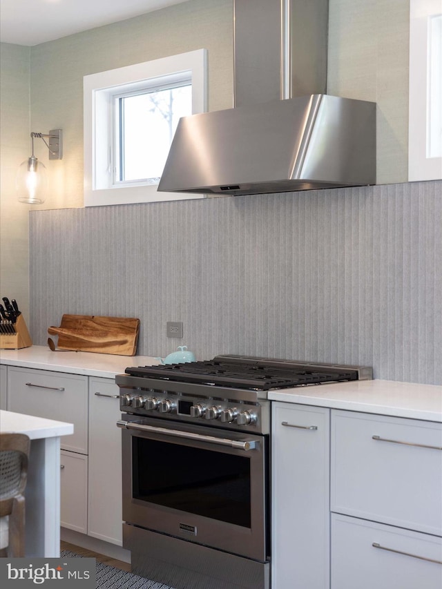 kitchen with light countertops, stainless steel range, and range hood