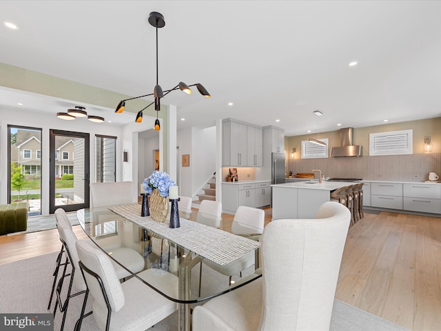 dining area featuring recessed lighting, light wood-style flooring, a notable chandelier, and stairway