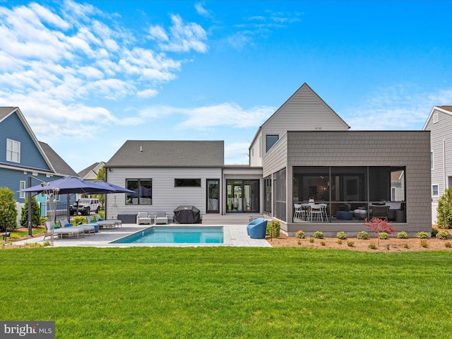 back of property with a yard, a sunroom, a patio area, and an outdoor pool