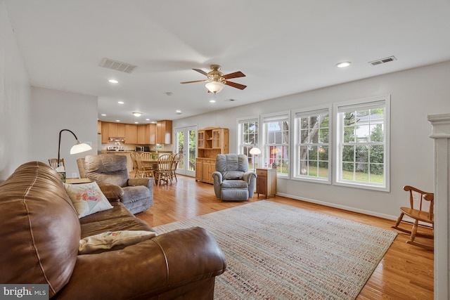 living area featuring a healthy amount of sunlight, ceiling fan, and visible vents