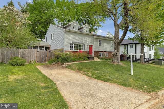 view of front of house featuring brick siding, fence, driveway, and a front yard