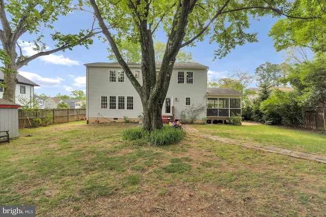 back of house featuring a lawn, crawl space, a fenced backyard, and a sunroom